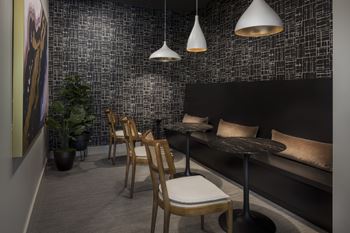 A black and white tiled wall with a wooden chair and table in front of it.